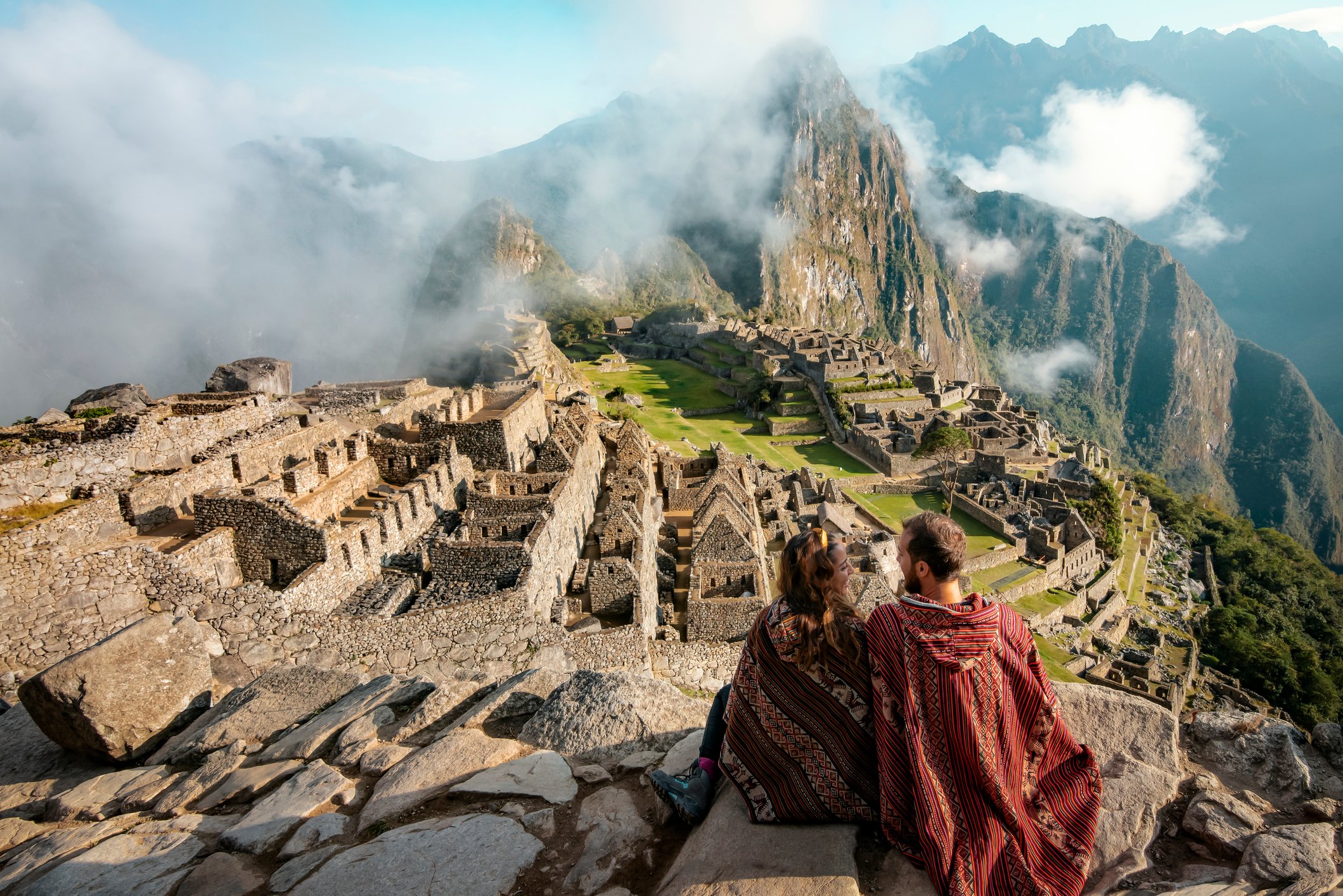 A couple sits atop the ancient Machu Picchu